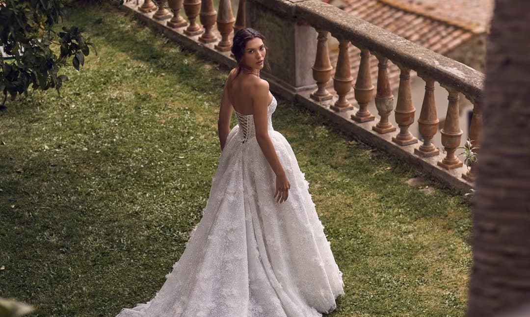 Side view of Hecate wedding dress with lace sleeves, corset bodice, and fitted satin skirt